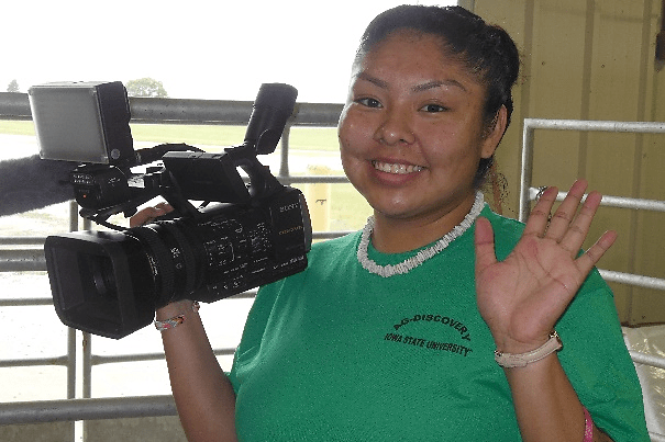 Female student holding a video camera and waving